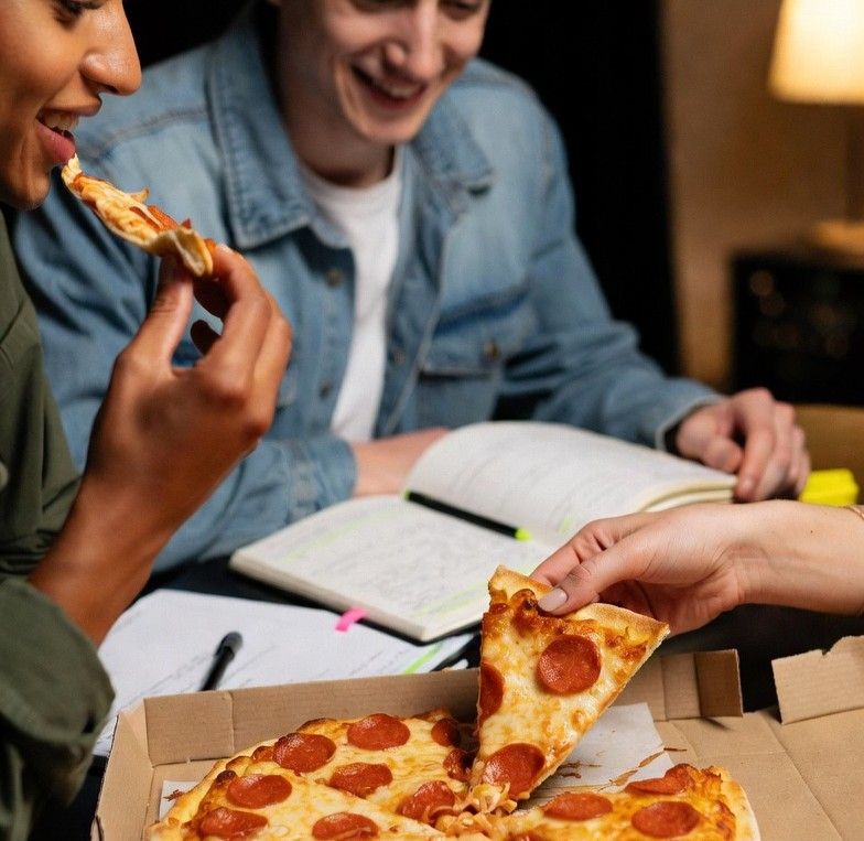 Friends sharing pizza while studying with highlighted notes