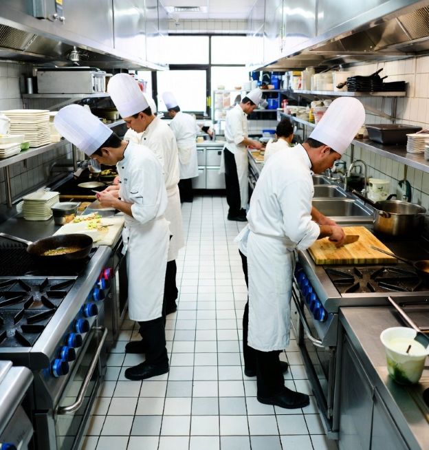 busy restaurant kitchen with chefs working over a spotless tiled floor